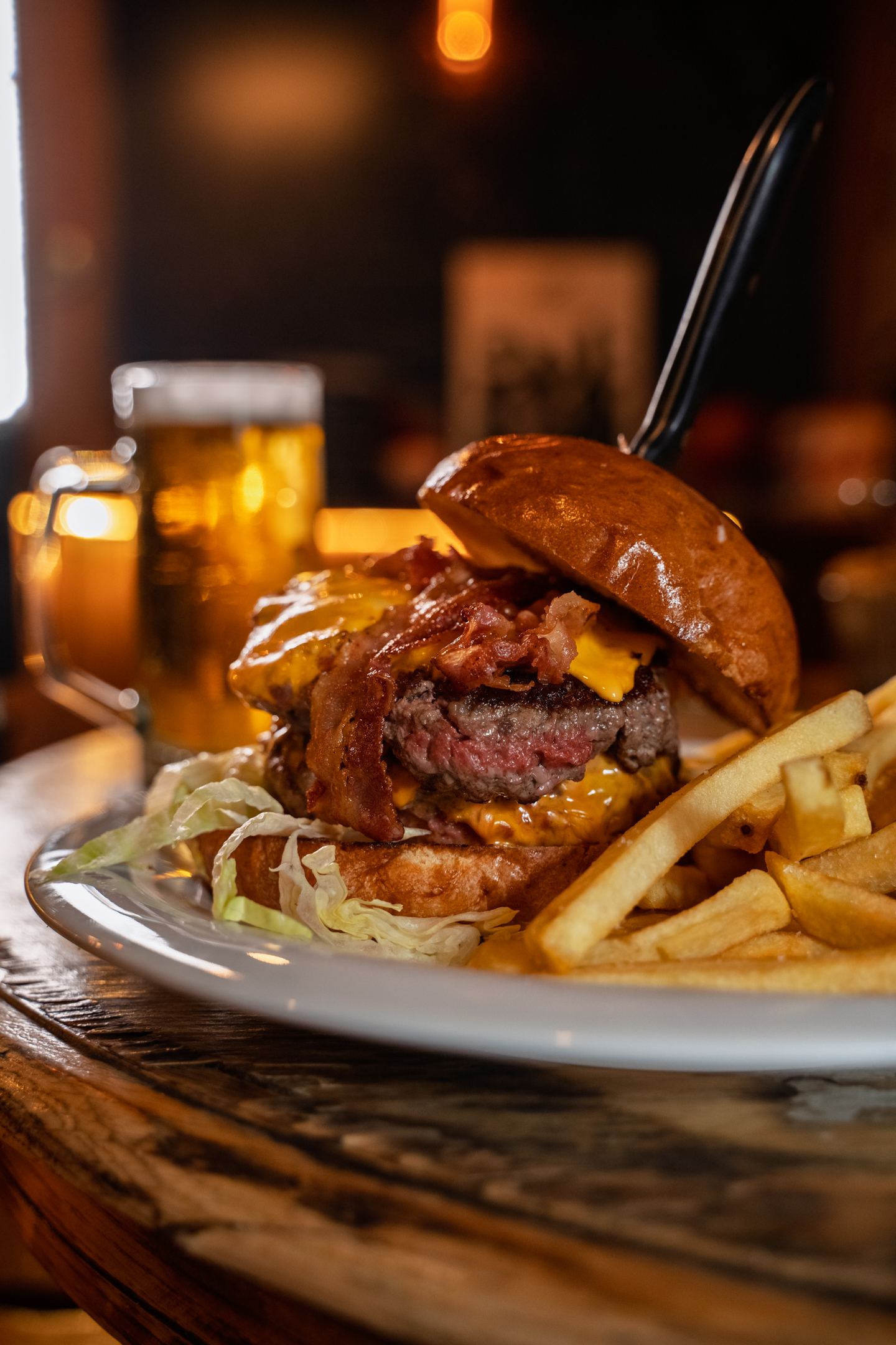 A beef burger with fries and a beer on tap